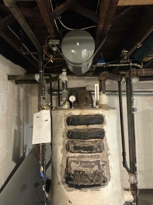 Conducted comprehensive boiler replacement estimate for century-old heating system in basement mechanical room. Evaluated existing boiler with extensive insulation deterioration, assessed removal requirements and clearances, documented current piping configuration including expansion tank and distribution lines, and provided multiple equipment options for complete system replacement to meet modern efficiency and safety standards.
