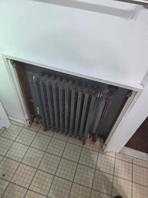 Performed inspection of boiler heating system with newer boiler unit connected to older distribution system. Identified multiple cast iron radiators throughout property exhibiting leaks at control valves and excessive operational noise. Documented deteriorated radiator conditions showing significant corrosion, rust accumulation on surfaces and fins, and failing valve connections with visible moisture damage. Recommended replacement of aging radiators and associated valve assemblies to eliminate leaks and restore quiet system operation.