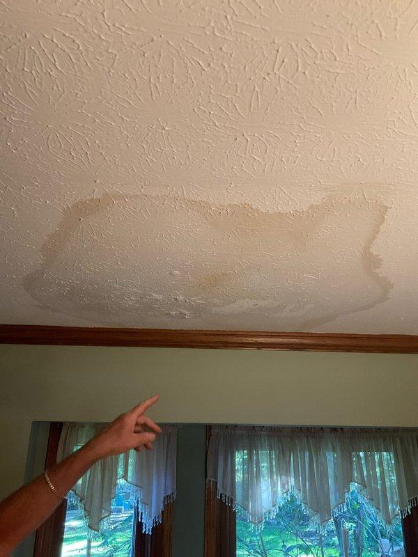 Responded to active water leak originating from shower valve assembly with visible water damage to dining room ceiling below. Upon inspection, identified significant moisture intrusion evidenced by brown discoloration and staining pattern on ceiling surface. Created access opening in wall to expose shower mixing valve and supply lines. Discovered failed connection at shower valve causing water to leak through wall cavity and penetrate dining room ceiling. Repaired compromised plumbing connection and addressed copper supply line configuration to restore proper water flow and eliminate leak source.