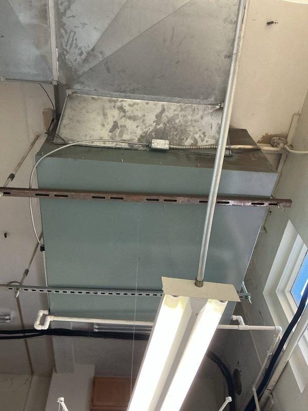 Conducted site assessment for HVAC replacement on commercial rooftop installation. Documented existing ductwork system showing aged metal supply duct with visible wear, weathered ceiling surfaces with water damage indicators, and supporting infrastructure requiring evaluation. Captured equipment positioning and structural conditions to develop comprehensive replacement estimate for system upgrade.
