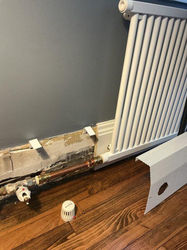 Responded to service call for radiator valve replacement. Upon arrival, removed existing failed Honeywell thermostatic radiator valve from baseboard heating system. Disconnected copper supply line from radiator, removed deteriorated baseboard trim to access valve assembly and fittings. Installed new Honeywell replacement valve with proper brass fittings, reconnected copper piping, and tested system for proper operation and leak-free connections. Radiator heating function restored to normal operation.