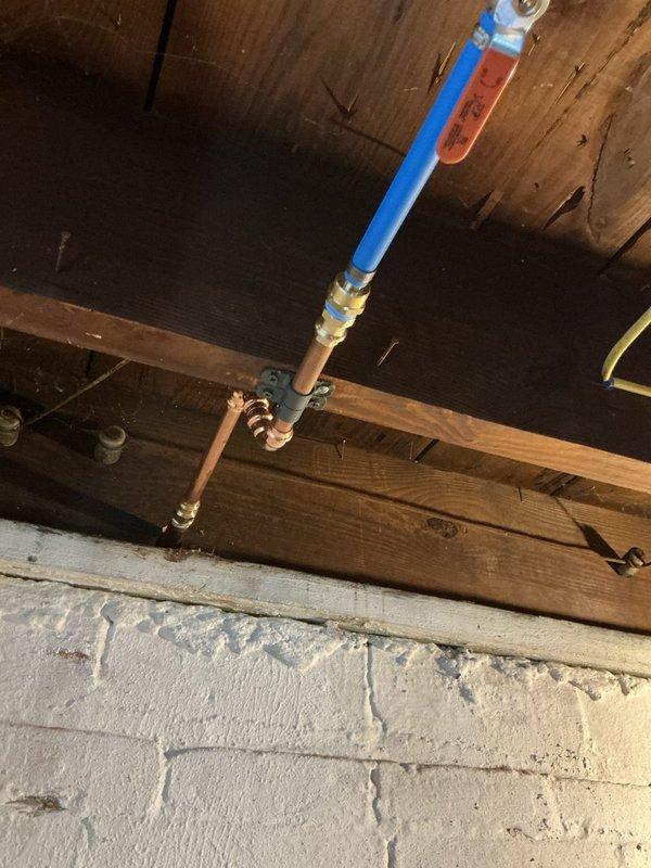 Responded to a burst water line feeding an outdoor spigot that had failed during the summer months. Accessed the supply line through the basement ceiling joists, removed the damaged section of pipe, and installed new blue PEX tubing with brass fittings to connect to the existing copper piping. Verified the outdoor hose bib mounted on the exterior brick wall was functioning properly and tested the system for leaks after restoring water pressure.