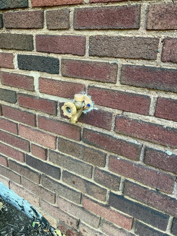 Responded to a burst water line feeding an outdoor spigot that had failed during the summer months. Accessed the supply line through the basement ceiling joists, removed the damaged section of pipe, and installed new blue PEX tubing with brass fittings to connect to the existing copper piping. Verified the outdoor hose bib mounted on the exterior brick wall was functioning properly and tested the system for leaks after restoring water pressure.