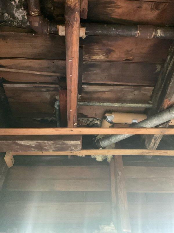 Responded to emergency plumbing call for multiple leaking pipes with exposed access through open ceiling soffit. Replaced deteriorated galvanized steel supply line and galvanized sink sanitary line that were actively leaking. Additionally addressed steam heating system issues by performing boiler skimming procedure on VEH boiler and repaired leaking steam supply pipe at joint connection. All repairs completed with accessible piping in exposed structural areas as documented in photos showing aged wooden joists and existing plumbing infrastructure.