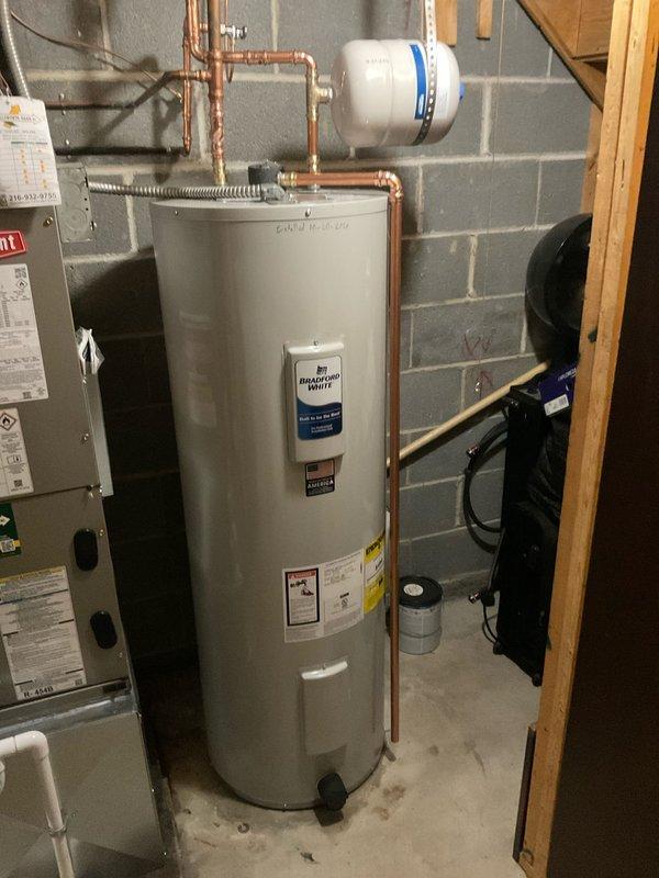 Removed and replaced the existing 50-gallon electric water heater with a new Bradford White unit, reconnecting the copper supply piping, expansion tank, and electrical supply, then tested for proper operation with no leaks. Also verified the water pressure reducing valve and shutoff valve assembly accessed through the wall opening.