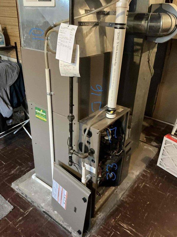 Performed an on-site replacement estimate for an existing gas-fired condensing furnace and air handler installation in the basement utility area. Inspected the unit with the access panel removed, documenting the burner compartment, wiring, PVC vent and condensate lines, black iron gas supply, copper refrigerant lines, and supply plenum/ductwork configuration. Equipment showed no visible frost, ice, rust, or damage, and unit data and existing layout were recorded to determine replacement scope and sizing.
