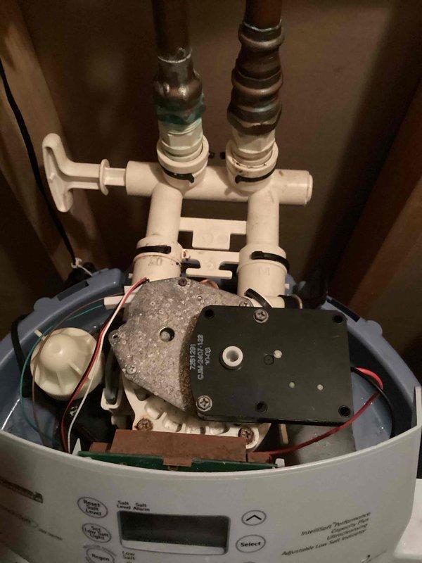 Diagnosed water softener with leaking bypass valve that had developed a crack at the connection point. Removed damaged bypass valve and installed new replacement unit. System tested after repair with successful results and no further leakage observed.