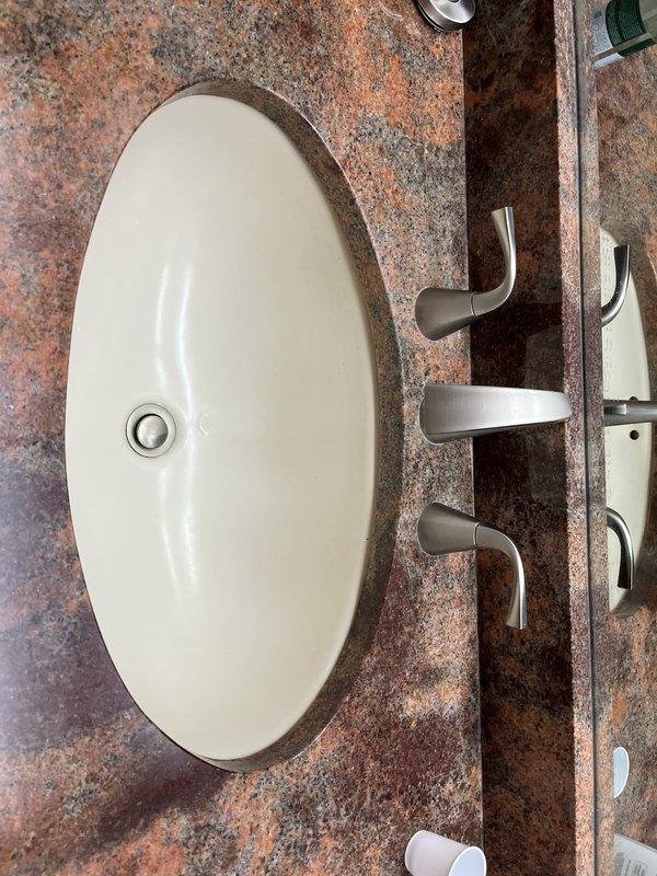 Removed plumbing connections and faucet assembly from hallway bathroom sink in preparation for new vanity installation. Disconnected supply lines and drain assembly, capping off plumbing as required. Will return for reinstallation of faucet and drain components when new vanity is in place.