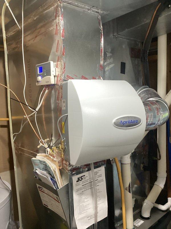 Successfully installed an AprilAire whole-home humidifier system connected to the existing Amana furnace. Installation included mounting the humidifier unit to ductwork, connecting the digital control panel with blue LCD display, and ensuring proper integration with home's plumbing system. System was tested and confirmed operational.