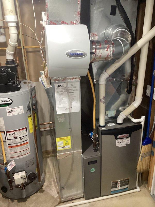 Successfully installed an AprilAire whole-home humidifier system connected to the existing Amana furnace. Installation included mounting the humidifier unit to ductwork, connecting the digital control panel with blue LCD display, and ensuring proper integration with home's plumbing system. System was tested and confirmed operational.