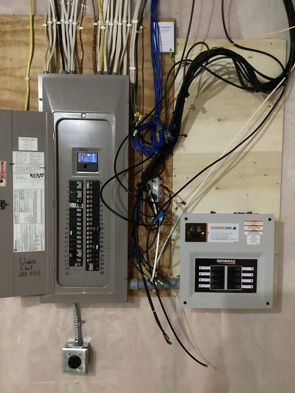 Completed installation of a Generac HomeLink transfer switch system, including final wiring connections between the main electrical panel and transfer switch. All circuit breakers were properly configured, and the system was successfully installed for battery backup functionality.