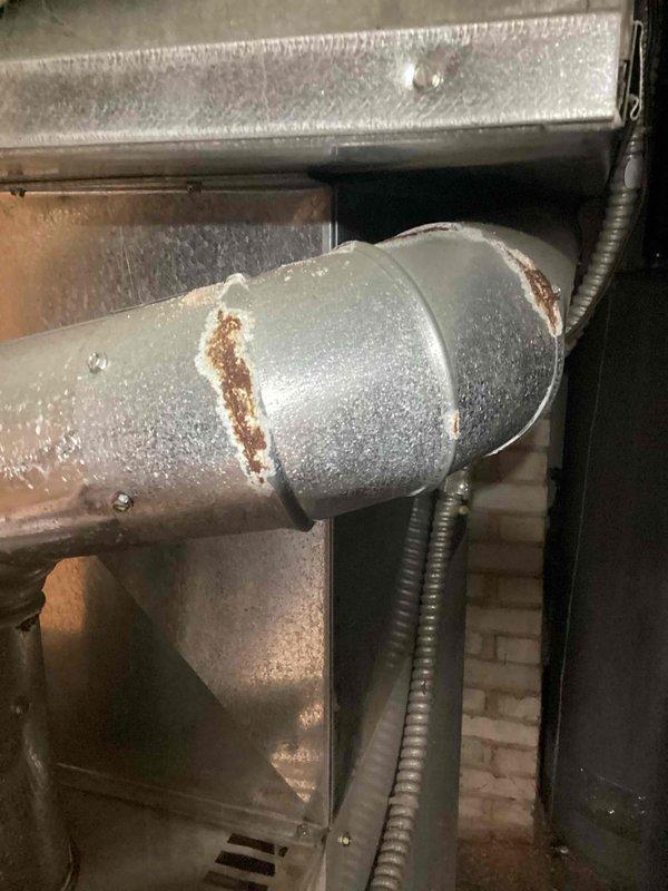 Responded to no heat service call for commercial property with 80% furnace experiencing intermittent operation. Inspection revealed significant corrosion and holes in the flue pipe, evidenced by visible rust and deterioration at connection points. Due to age, condition, and safety concerns with flue pipe integrity, recommended complete system replacement.