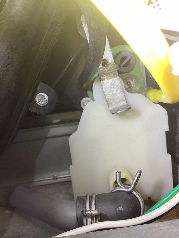 Responded to customer complaint of antifreeze smell in living room. Upon inspection, discovered glycol leak from boiler system reservoir, evidenced by fluid pooling on concrete floor beneath the unit. Located and documented the faulty reservoir connection with visible fluid discharge.