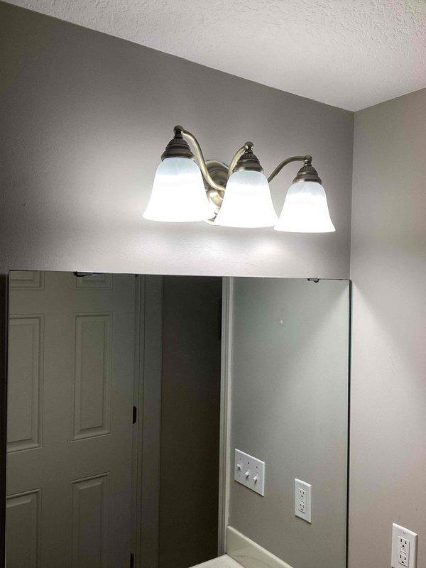 Completed installation of new outdoor receptacle on existing garage switch circuit. Replaced two bathroom vanity light fixtures, each with three bell-shaped frosted glass shades and brushed nickel finish. Installed new exterior light fixture per approved bid specifications.