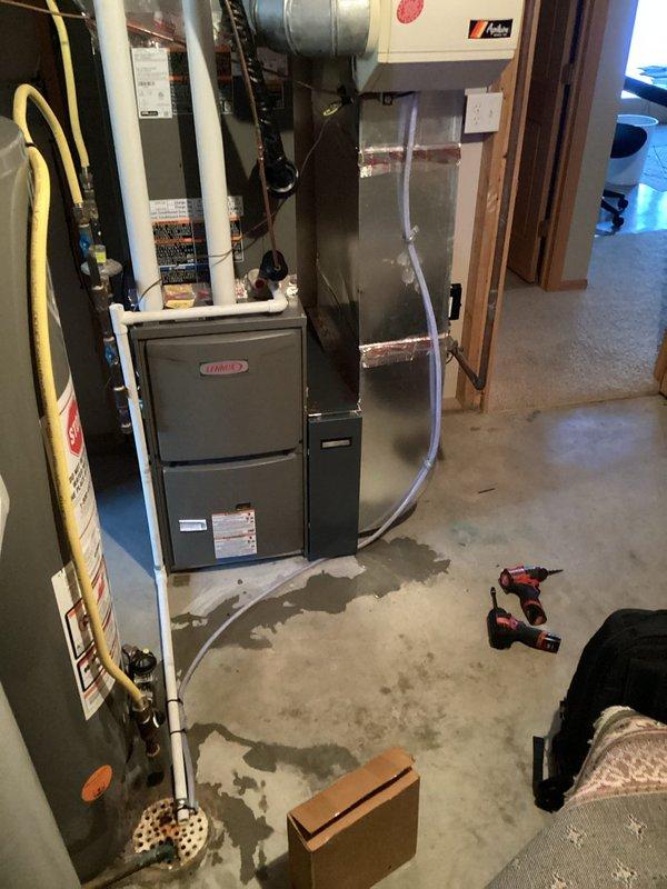 Located water leak on floor originating from humidifier connected to Lennox furnace system. Identified damaged drain line as the source of leakage and replaced it to restore proper drainage and prevent further water accumulation on concrete floor.