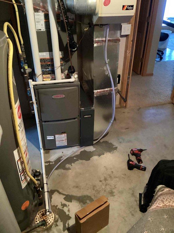 Located water leak on floor originating from humidifier connected to Lennox furnace system. Identified damaged drain line as the source of leakage and replaced it to restore proper drainage and prevent further water accumulation on concrete floor.