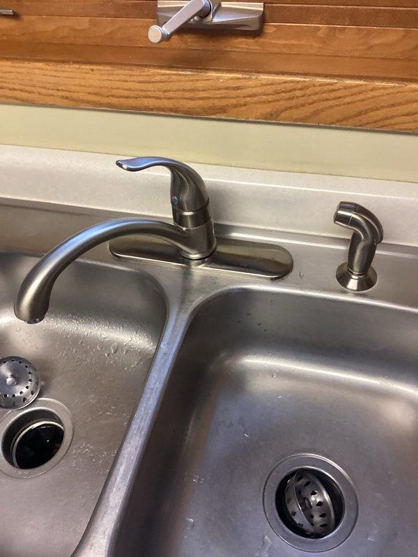 Responded to service call for kitchen faucet leak and non-working garbage disposal. Successfully removed old kitchen faucet and installed customer-supplied replacement unit in stainless steel double-basin sink. Verified proper connections, restored water service, and confirmed proper operation of the new brushed nickel single-handle faucet with all components functioning correctly.