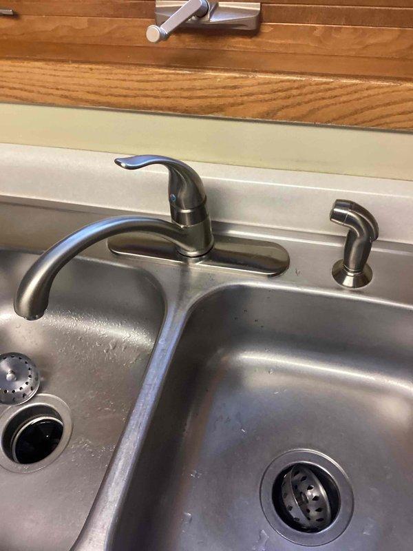 Responded to service call for kitchen faucet leak and non-working garbage disposal. Successfully removed old kitchen faucet and installed customer-supplied replacement unit in stainless steel double-basin sink. Verified proper connections, restored water service, and confirmed proper operation of the new brushed nickel single-handle faucet with all components functioning correctly.