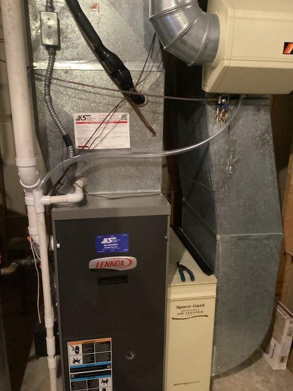 Responded to callback regarding water overflow from humidifier drain after previous tune-up service. Identified issue with uneven floor drain causing water to back up under floor tiles. Resolved by rerouting humidifier drain hose directly to PVC drain pipe off furnace to ensure proper drainage into floor drain, preventing further water damage to flooring.