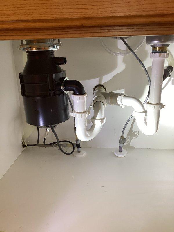 Successfully installed new kitchen faucet with side sprayer and reconnected existing garbage disposal. Verified proper water flow and drainage through the double basin sink, confirming no leaks at connection points throughout the P-trap configuration and disposal unit.