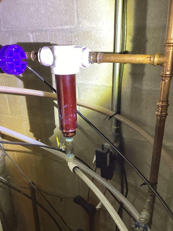 Responded to a service call regarding severely low water pressure throughout the residence. Diagnostic testing revealed good water pressure in the basement up to the whole house filtration system, but significant pressure drop after the Culligan brand softener. Visual inspection confirmed the whole house filter requires cleaning or replacement, and the iron filter and softener need professional servicing. Advised customer to contact Culligan directly to service their filtration system components to restore proper water pressure to the home.