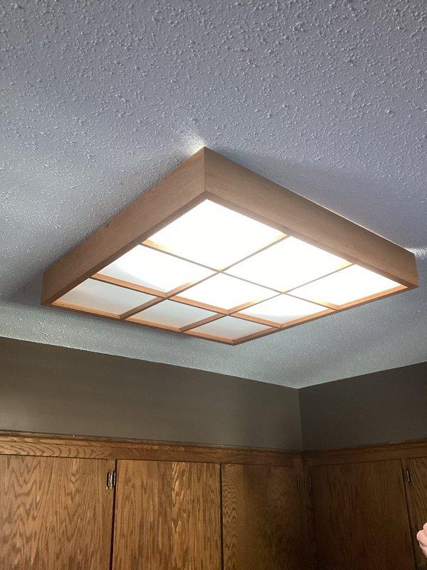 Installed customer-provided ceiling fan in living room, running 3-wire cable from existing 2-gang switch box to center of room between railing and exterior wall. Removed old kitchen light fixture that exhibited burnt plastic smell during extended operation and replaced with new customer-provided fixture, ensuring all installations meet electrical code requirements.