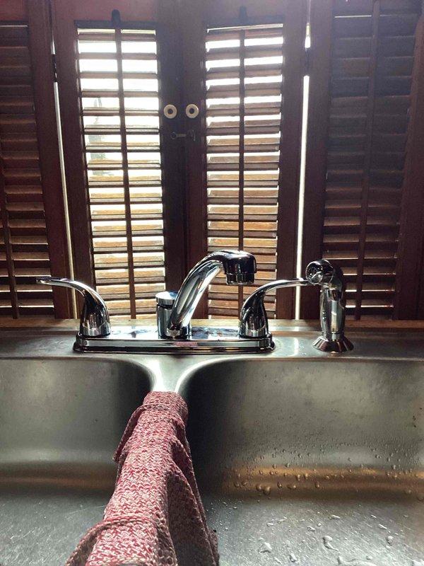 Successfully removed existing Moen kitchen faucet and installed customer-supplied replacement Moen model with side sprayer. Completed all necessary connections and performed functionality test with positive results - all components operating properly with no leaks observed.