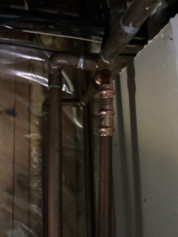 Identified and repaired a pin hole leak on a 3/4" copper supply line located directly above the water softener. Removed the damaged section of copper pipe and 90° fitting, then replaced with new copper pipe and fitting. System tested after repair with water restored and verified proper function with no leaks.