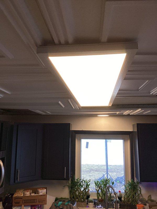 Successfully installed two customer-supplied interior light fixtures - one large rectangular recessed fixture with warm white illumination in a coffered ceiling kitchen area, and one circular recessed fixture in a ceiling section. Both installations were completed according to specifications with proper electrical connections and secure mounting.