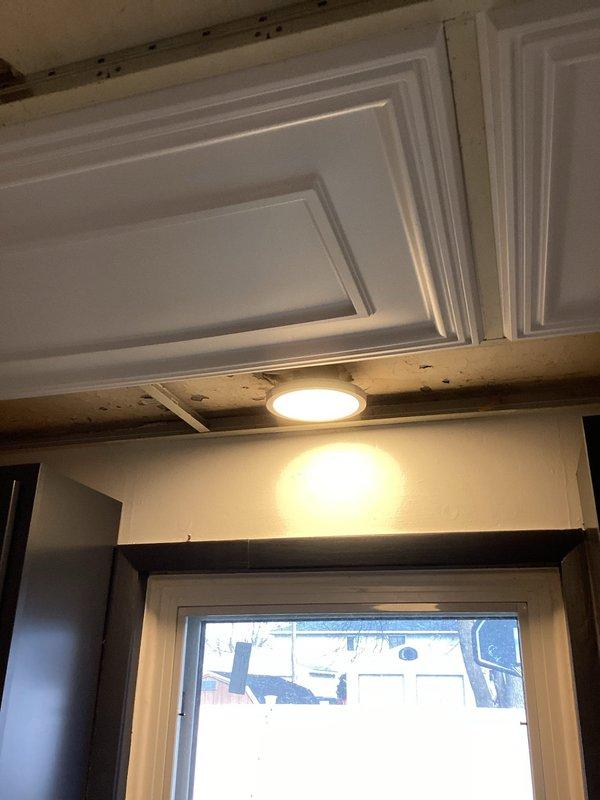 Successfully installed two customer-supplied interior light fixtures - one large rectangular recessed fixture with warm white illumination in a coffered ceiling kitchen area, and one circular recessed fixture in a ceiling section. Both installations were completed according to specifications with proper electrical connections and secure mounting.