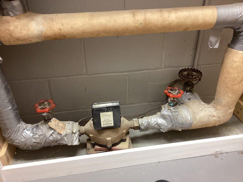 Completed inspection of residential plumbing system, documenting PVC drainage components in utility area and examining water supply configuration with insulated pipes, flow control device, and dual shut-off valves mounted against cinder block wall. System appears functional with some minor insulation wear noted on piping.