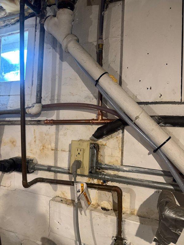 Responded to service call for basement water leak. Located and repaired pinhole leak in 1/2" copper fitting by replacing affected section of pipe. Inspected water heater and surrounding plumbing connections to ensure no additional leaks were present.