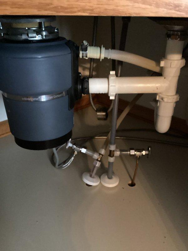 Removed kitchen faucet and garbage disposal unit to prepare for scheduled countertop installation. Documented existing double-basin sink setup with current disposal connection and drain configuration. Will return after countertop installation to install customer-supplied replacement faucet and garbage disposal.