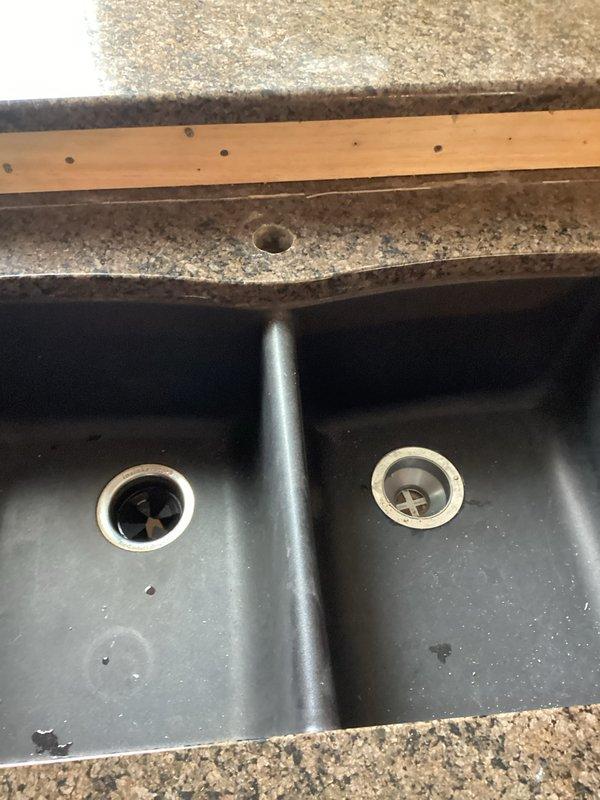 Removed kitchen faucet and garbage disposal unit to prepare for scheduled countertop installation. Documented existing double-basin sink setup with current disposal connection and drain configuration. Will return after countertop installation to install customer-supplied replacement faucet and garbage disposal.