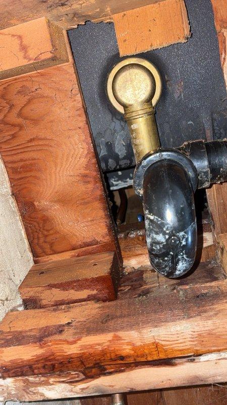 Arrived for scheduled service to address a small leak behind tub that was leaking into basement. Upon arrival, customer was not present and could not be reached by phone. Visual inspection of shower enclosure revealed likely source of leak at corner junction of decorative panels, with evidence of water damage visible in basement at P-trap connection showing mineral deposits and possible deterioration.