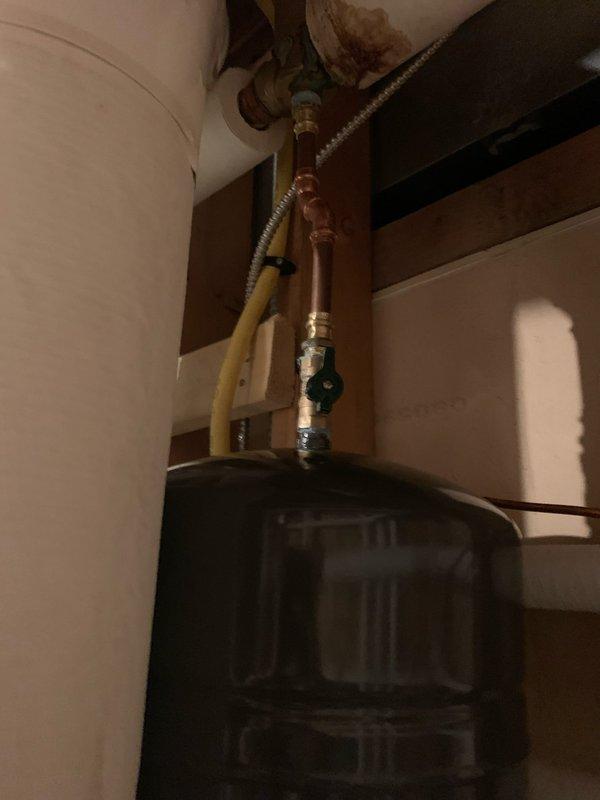 Installed expansion tank in utility area with proper copper pipe connections. System includes black cylindrical tank integrated into existing plumbing network with appropriate valves and fittings. Service completed between 10-12pm as scheduled.