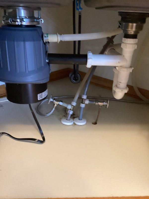 Reinstalled customer-supplied kitchen faucet and garbage disposal in double-basin stainless steel sink. Made all necessary plumbing connections including PVC drain assembly and P-trap installation. Tested both fixtures for proper operation with successful results.