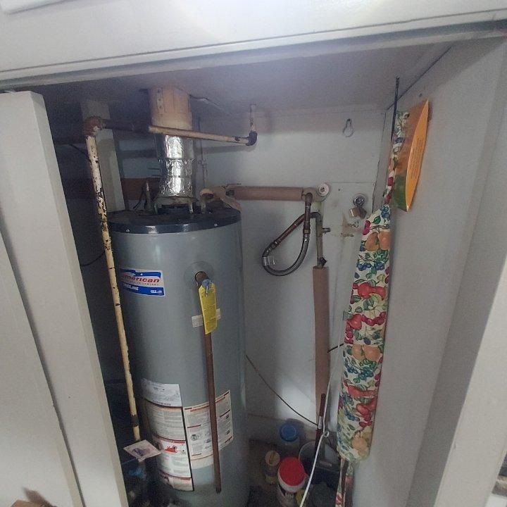 Responded to emergency call for pinhole leak at water heater supply line that was spraying water onto the pilot light and causing smoke. Upon inspection, identified failed soldered joint at 1/2" copper 90-degree fitting on the cold water inlet to the American brand water heater. Cut out the defective fitting and section of copper pipe, then installed new 1/2" copper 90-degree fitting with proper soldering techniques. Restored water supply to the home and verified all connections were secure with no leaks. Tested water heater operation to confirm proper function and that pilot light was no longer affected by moisture.