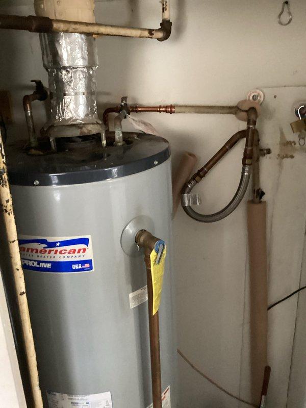 Responded to emergency call for pinhole leak at water heater supply line that was spraying water onto the pilot light and causing smoke. Upon inspection, identified failed soldered joint at 1/2" copper 90-degree fitting on the cold water inlet to the American brand water heater. Cut out the defective fitting and section of copper pipe, then installed new 1/2" copper 90-degree fitting with proper soldering techniques. Restored water supply to the home and verified all connections were secure with no leaks. Tested water heater operation to confirm proper function and that pilot light was no longer affected by moisture.