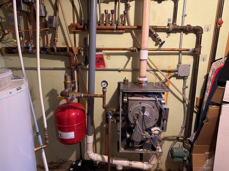 Responded to no heat call and found 20-year-old boiler system (installed May 2006) with failed heat exchanger and non-operational indirect tank pump, resulting in complete loss of flame and heating capability. Conducted thorough diagnostic assessment of the multi-zone heating system including inspection of zone valves, copper piping network, expansion tank, and boiler internal components. Documented system condition with photos and provided customer with repair and replacement estimates for failed equipment.