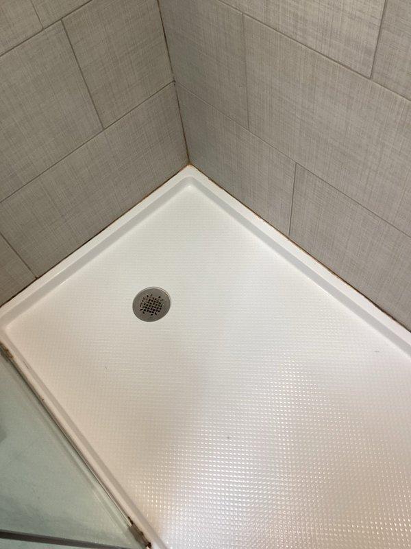 Removed deteriorating caulking from master bathroom stand-up shower enclosure where moisture intrusion was evident at tile-to-shower pan seams. Thoroughly cleaned and prepped all joints, then applied fresh silicone caulk around the perimeter of the shower base where it meets the tiled walls. Advised to allow 4-6 hours cure time before water exposure.