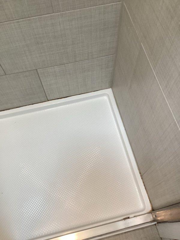 Removed deteriorating caulking from master bathroom stand-up shower enclosure where moisture intrusion was evident at tile-to-shower pan seams. Thoroughly cleaned and prepped all joints, then applied fresh silicone caulk around the perimeter of the shower base where it meets the tiled walls. Advised to allow 4-6 hours cure time before water exposure.