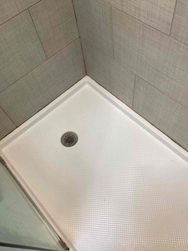 Returned to address callback for shower caulking quality concerns. Removed previously applied fresh caulk from shower surround and re-caulked all seams between the textured acrylic shower pan and surrounding tile walls to ensure proper water-tight seal and improved aesthetic finish.