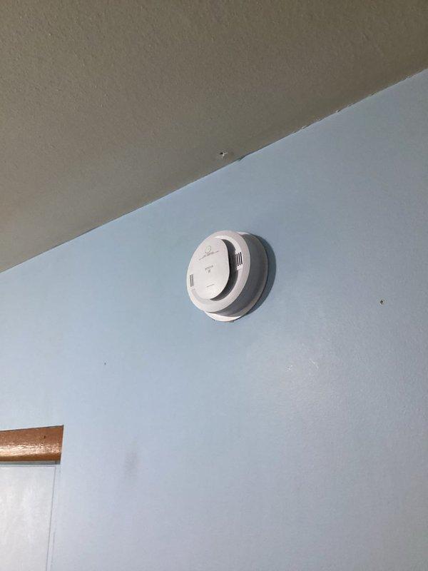 Installed combination smoke and carbon monoxide detector in hallway per approved bid. Ran 14-3 wiring from existing bedroom smoke detector to new hallway unit to ensure proper interconnection between devices. Both detectors tested and verified operational with LED indicators functioning correctly.