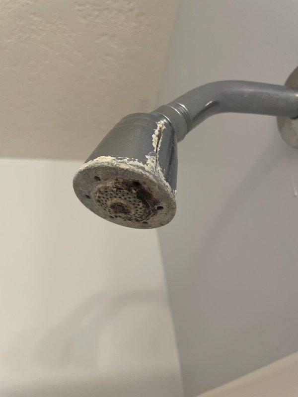 Responded to master bathroom shower issue where handle was falling off valve and shower head was spraying erratically during use. Upon inspection, found severe corrosion on both the shower handle and shower head, with significant mineral buildup and deterioration affecting proper operation. Removed corroded shower handle from valve assembly and replaced with new chrome fixture. Removed existing shower head displaying extensive mineral deposits and corrosion, then installed new replacement unit. Tested system operation to verify proper handle engagement with valve and confirmed shower head spray pattern functioned correctly without leakage.