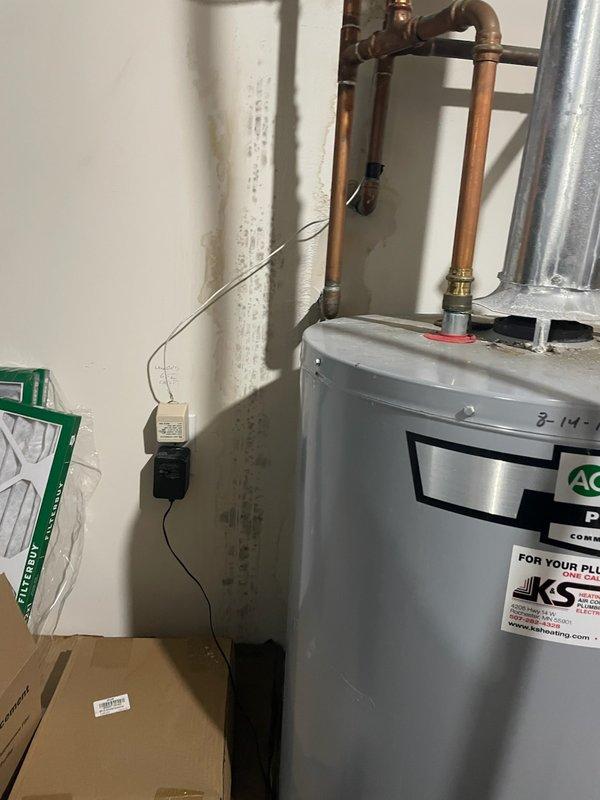 Responded to a water leak emergency near the water heater system. Upon arrival, identified a pinhole leak in the quarter-inch nylon supply line connected to the humidifier solenoid, which was causing moisture damage to the surrounding drywall. Replaced the defective nylon line with a quarter-inch copper line to prevent future failures, completing the repair under the humidifier warranty as the original installation should have utilized copper tubing. Documented the water damage and completed plumbing connections with proper fittings.