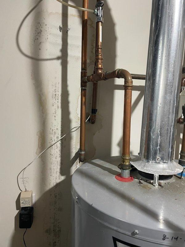 Responded to a water leak emergency near the water heater system. Upon arrival, identified a pinhole leak in the quarter-inch nylon supply line connected to the humidifier solenoid, which was causing moisture damage to the surrounding drywall. Replaced the defective nylon line with a quarter-inch copper line to prevent future failures, completing the repair under the humidifier warranty as the original installation should have utilized copper tubing. Documented the water damage and completed plumbing connections with proper fittings.
