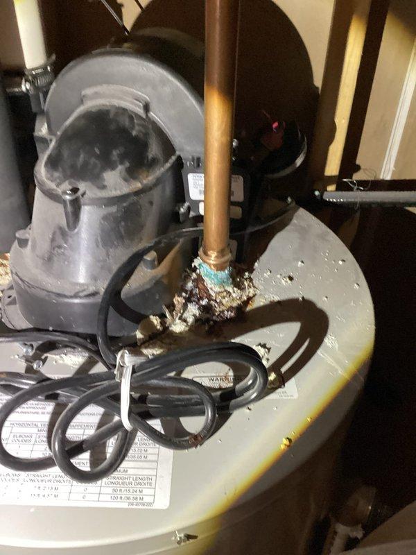 Responded to service call for gas-fired tanked water heater that would not remain lit and was continuously refiring. Upon inspection, discovered severely corroded inlet and outlet connections with active leaking at both connection points. Corrosion extended to internal water heater adaptors, rendering the unit unrepairable. Additionally, the gas control valve displayed a diagnostic fault code indicating pressure switch malfunction—either stuck open or closed position. Attempted to reset the pressure switch, but unit continued to experience ignition failure and would not maintain flame. Visual inspection revealed significant rust staining and mineral deposits throughout the tank exterior, with pronounced copper oxidation (green-blue corrosion) at pipe connections indicating long-term water intrusion. The 6-year-old Bradford White power vent unit was determined to be a total loss due to multiple system failures including compromised water connections, internal leak damage, and gas contro