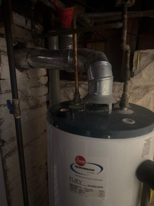 Responded to service call for water heater with pilot light failure. Upon arrival, diagnosed that the pilot would not remain lit, indicating a faulty thermocouple or gas valve assembly. Due to the age and condition of the existing unit, performed complete water heater replacement. Removed old Rheem Guardian tanked water heater from basement utility room and installed new residential gas-fired water heater. Connected all supply and discharge plumbing lines, installed proper venting through existing ductwork with metallic elbow configuration, and ensured all gas connections were secure and leak-free. Tested unit operation, verified pilot ignition and burner function, and confirmed proper temperature and pressure relief valve installation. Left installation area clean with all plumbing connections properly secured.