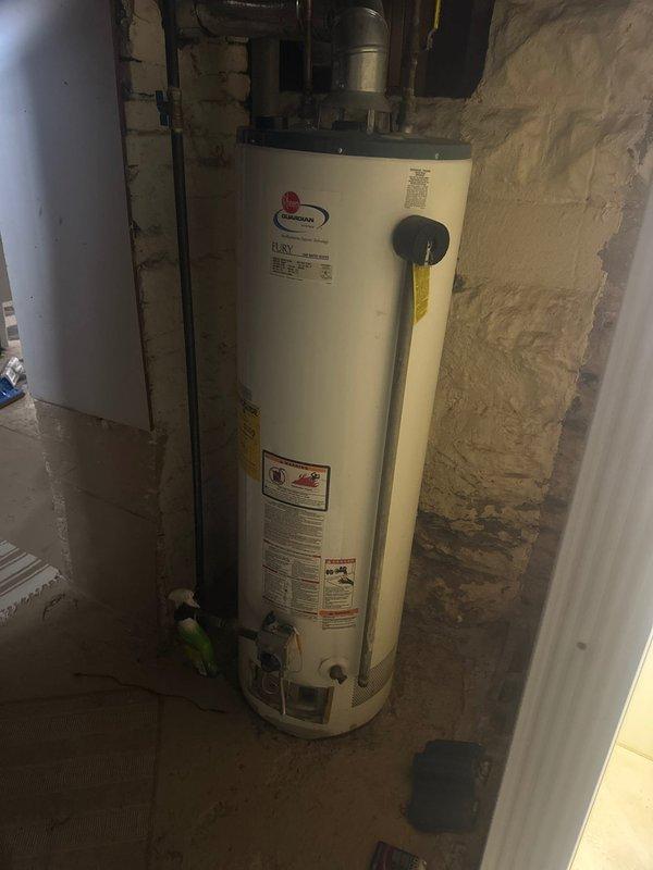 Responded to service call for water heater with pilot light failure. Upon arrival, diagnosed that the pilot would not remain lit, indicating a faulty thermocouple or gas valve assembly. Due to the age and condition of the existing unit, performed complete water heater replacement. Removed old Rheem Guardian tanked water heater from basement utility room and installed new residential gas-fired water heater. Connected all supply and discharge plumbing lines, installed proper venting through existing ductwork with metallic elbow configuration, and ensured all gas connections were secure and leak-free. Tested unit operation, verified pilot ignition and burner function, and confirmed proper temperature and pressure relief valve installation. Left installation area clean with all plumbing connections properly secured.